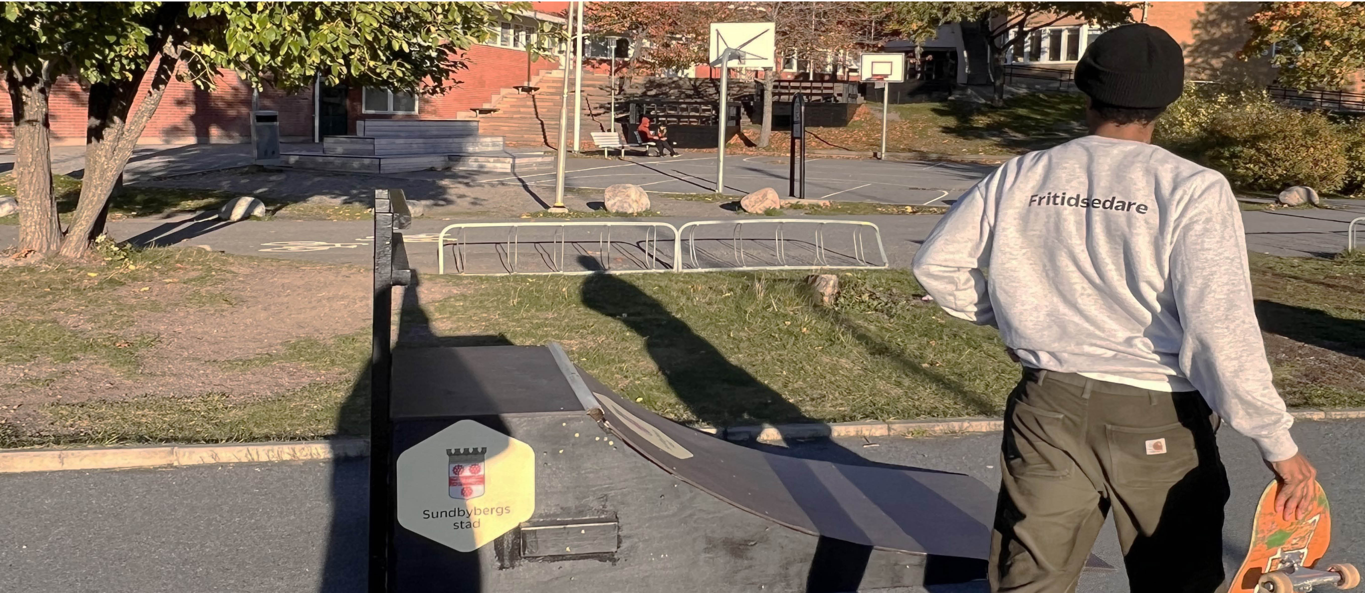 Fritidsledare som bär en skateboard bredvid en ramp