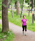 Kvinna i rosa tröja som joggar på en gångväg