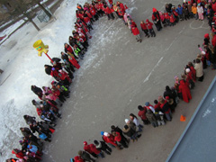 Elever på Lilla Alby skola står på skolgården i en formation som bildar ett hjärta - för gemenskap och trygghet.