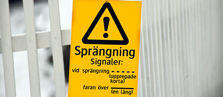 Varningsskylt för sprängningsarbete som visar signal för sprängning och faran över.