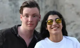 Två ungdomar, en pojke och en flicka, tittar in i kameran. Flickan har ett par solglasögon på sig.