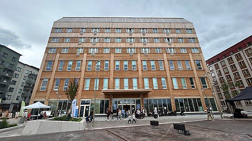 Stor, modern byggnad med träfasad. Några personer rör sig framför huset.